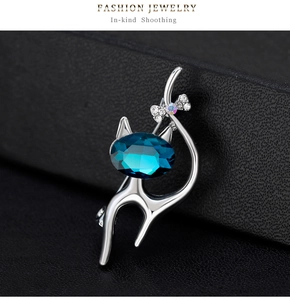 Détail de la broche chat avec cristal bleu foncé et nœud en strass sur cuir noir