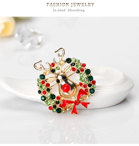 Detail of Christmas reindeer brooch with red bow and crystal wreath on white leaf tray