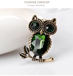 Dettaglio macro di spilla a forma di gufo vintage con cristalli verde smeraldo