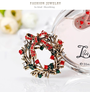 Detail shot of a Christmas wreath brooch with red bow and colorful rhinestones on a marble base