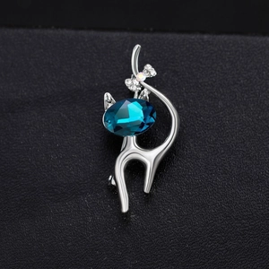 Broche chat élégante en métal argenté avec un grand cristal bleu foncé et un nœud