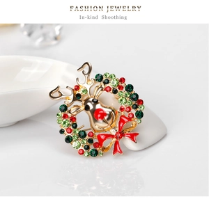 Detailed view of Christmas wreath brooch with reindeer head and red bow on ceramic display