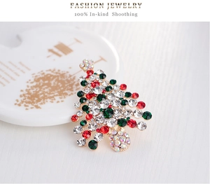 Détails d'une broche en forme de sapin de Noël avec strass rouges et verts