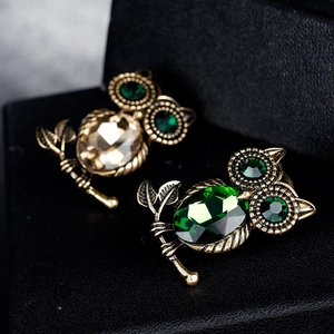 Dettaglio di spille a forma di gufo vintage con cristalli verdi e color champagne