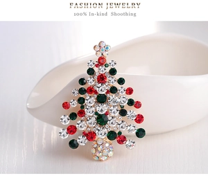 Détail d'une broche en forme de sapin de Noël avec des strass colorés sur une assiette