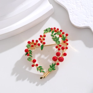 Macro view of heart-shaped brooch with green enamel leaves and red berry details