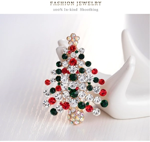 Détail macro de la broche sapin de Noël avec strass colorés sur un support main