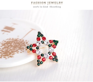 Détail macro de broche étoile de Noël avec strass rouges et verts sur socle doré