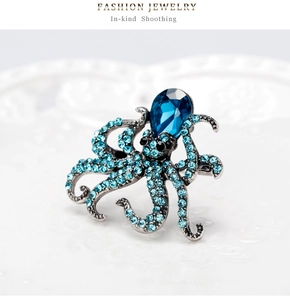 Macro view of octopus brooch with blue rhinestones and teardrop gem on white background