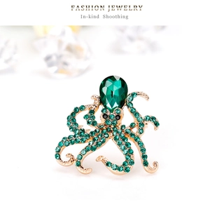 Macro detail of octopus brooch featuring emerald green crystals and gold-plated finish