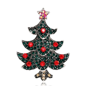 Close-up of Christmas tree brooch with green crystals and red rhinestones on silver base