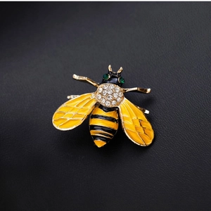 Exquisite bee brooch with yellow enamel and sparkling rhinestones on black background