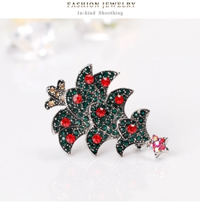 Detailed view of Christmas tree brooch with green rhinestones and a purple star charm