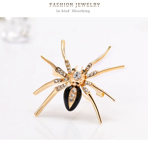 Detail van gouden insecten spin broche met kristallen strassteentjes en groene ogen