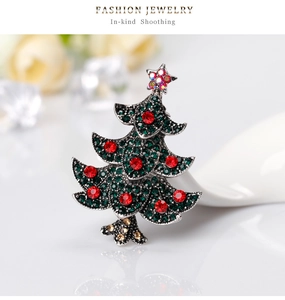Detailed close-up of a Christmas tree brooch with emerald rhinestones and silver metal base