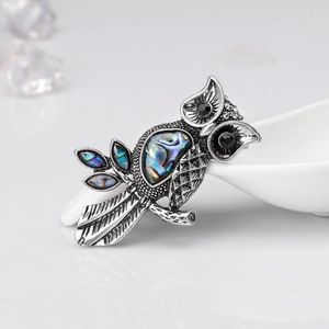 Macro detail of retro owl brooch featuring iridescent abalone shell inlay and aged silver