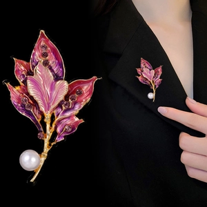 Close-up of luxury leaf brooch with purple enamel, sparkling rhinestones and a white pearl