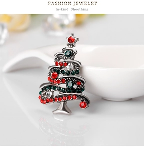 Macro view of Christmas tree brooch with colorful rhinestones on a ceramic surface