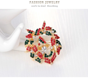 Macro detail of Christmas wreath brooch with red and green rhinestones and a gold bell