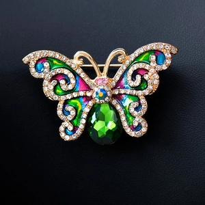 Elegante spilla a farfalla dorata con smalto colorato e strass lucidi su pelle nera