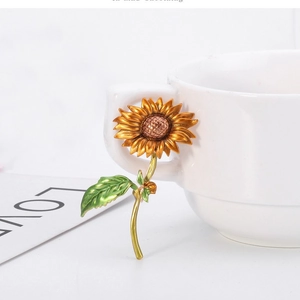 Broche tournesol exquise avec pétales jaunes et feuilles vertes sur une tasse blanche