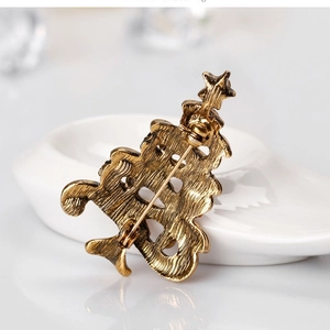 Vintage gold Christmas tree brooch showing secure pin fastener back on white stand