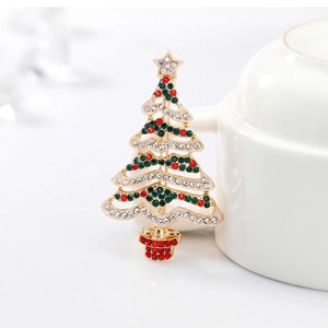Christmas tree brooch with colorful rhinestones on gold alloy base leaning on a cup