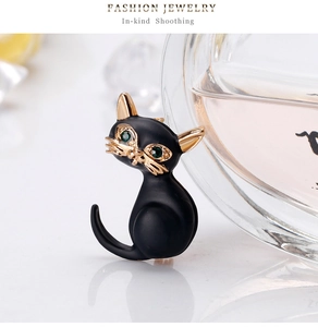 Detailansicht einer eleganten schwarzen Katzenbrosche mit grünen Augen und Vergoldung