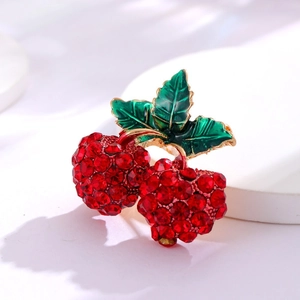 Broche cerise élégante avec strass rouges et feuille d'émail vert sur un support blanc