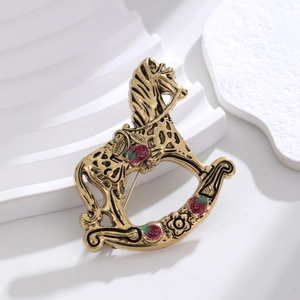 Détail d'une broche cheval à bascule vintage or avec motifs de roses en émail