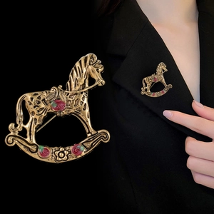 Détail de la broche cheval à bascule doré vintage avec rose émaillée sur blazer noir