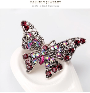 Macro detail of a vintage silver butterfly brooch featuring red rhinestones and filigree
