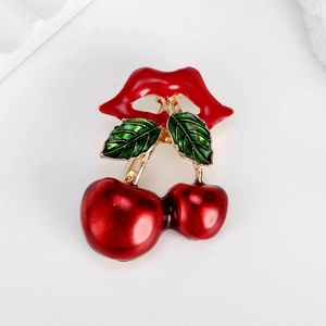 Creative red cherry and lips brooch in gold alloy finish on a minimalist white backdrop