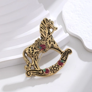 Broche cheval à bascule dorée vintage avec détails de roses rouges sur fond blanc pur