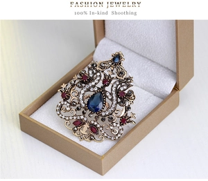 Dettaglio di una spilla vintage stile palazzo con strass colorati in una confezione regalo