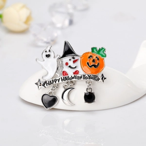 Dettaglio della spilla di Halloween con ciondoli a fantasma e zucca su un cucchiaio di porcellana