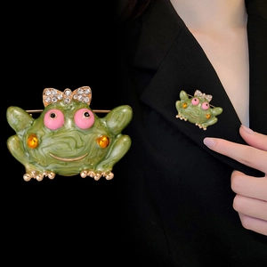 Detail of green enamel frog brooch with rhinestone bow on a black suit lapel