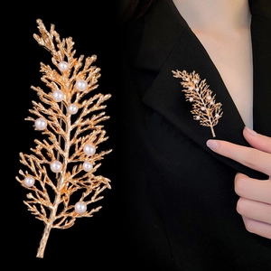 Dettaglio di un'elegante spilla a foglia dorata con perle su un bavero di velluto