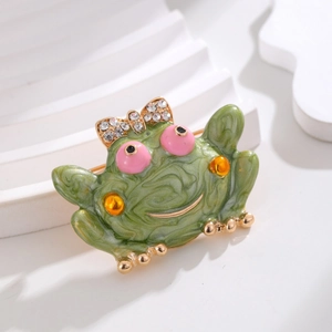 Elegant green enamel frog brooch with diamond bow accessory on a minimalist background