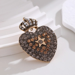Detail of vintage gold crown heart brooch with crystals and faux pearl on white stand