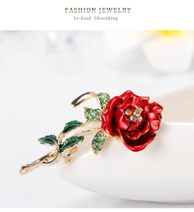 Detailed close-up of red rose brooch with enamel petals and crystal-studded gold setting