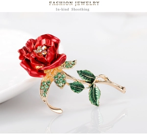 Detail of handcrafted red rose brooch with green enamel leaves and sparkling rhinestones