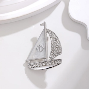 Broche voilier argentée élégante avec strass brillants et détails en émail blanc