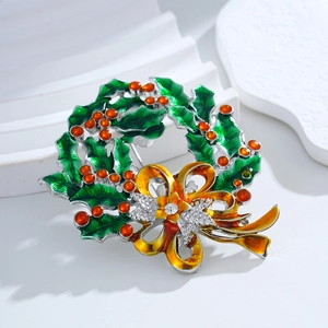 Christmas wreath brooch with green holly leaves, red bow, and crystal rhinestones