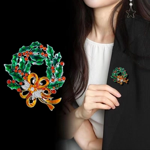 Christmas wreath brooch with green holly leaves, red berries, and a sparkling crystal