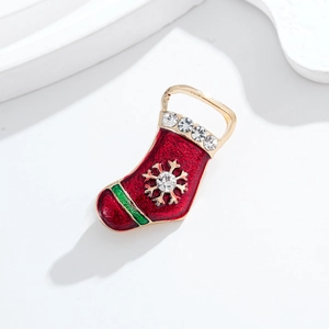 Spilla calza di Natale con strass e fiocco di neve dorato su sfondo bianco pulito