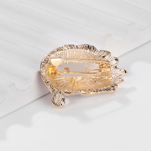 Back view of gold plated feather brooch with long pin clasp on white platform