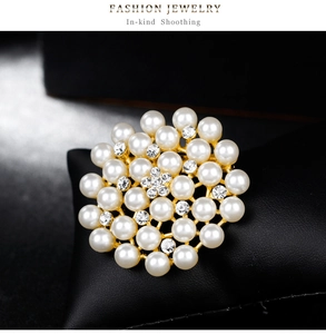 Vue macro d'une broche fleur avec perles blanches et strass brillants sur socle doré