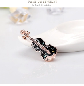 Détail d'une broche violon en or rose avec émail noir et incrustation de coquillages