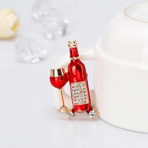 Dettaglio di una spilla a forma di bottiglia di vino smaltata rossa con strass